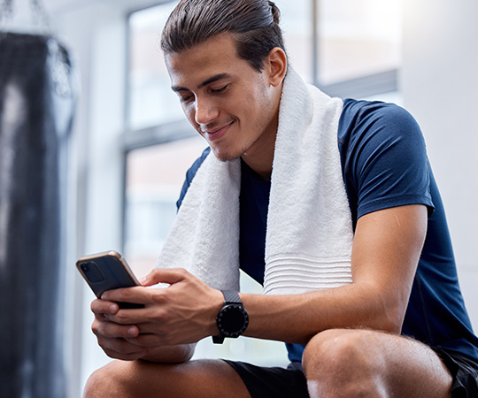 young_man_on_phone_sitting_in_gym_552564409